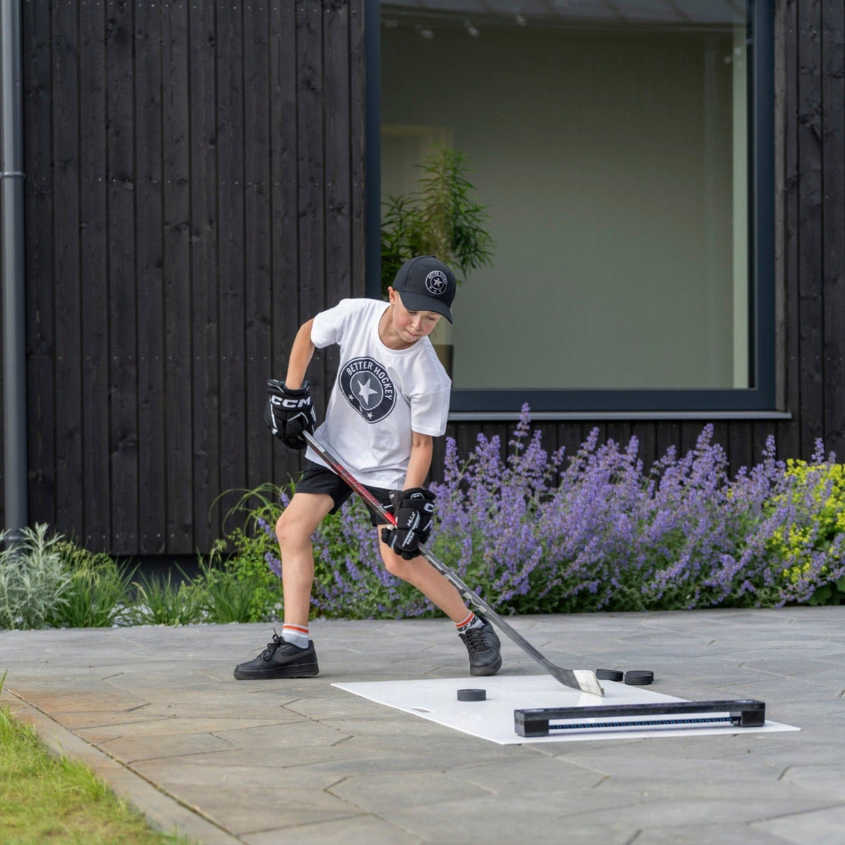 Ung spelare tränar puckkontroll och passningar med hockeypassaren på utegården.