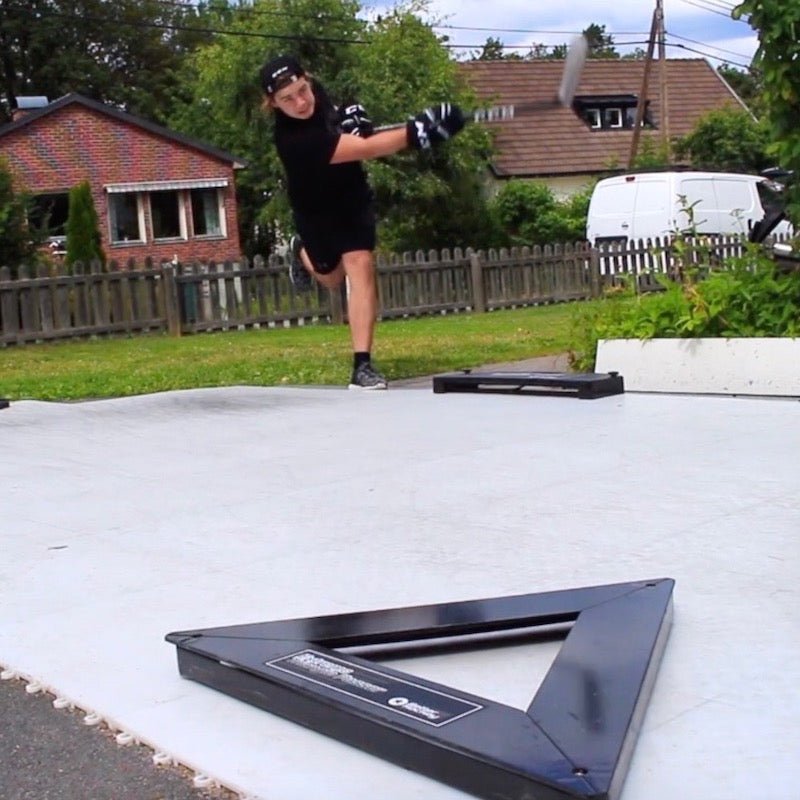 En spelare testar Extreme Hockey Flooring Tiles utomhus medan han slår pucken på den plastiska ytan för att simulera is.