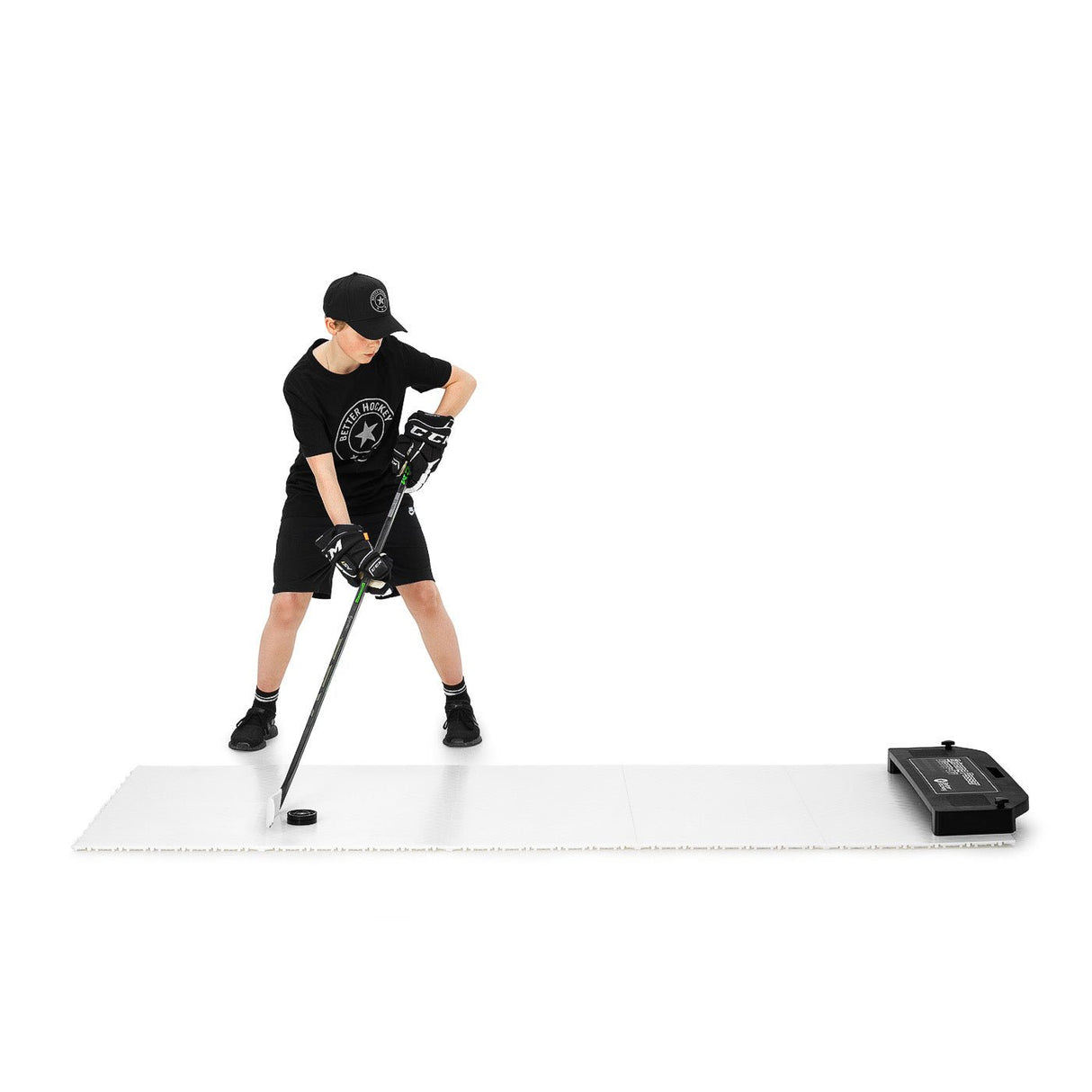 Ung kille tränar passningar med hockeyklubba och puck på Extreme Hockey Flooring Tiles Passing Kit, perfekt för skottramp och hockeymål.