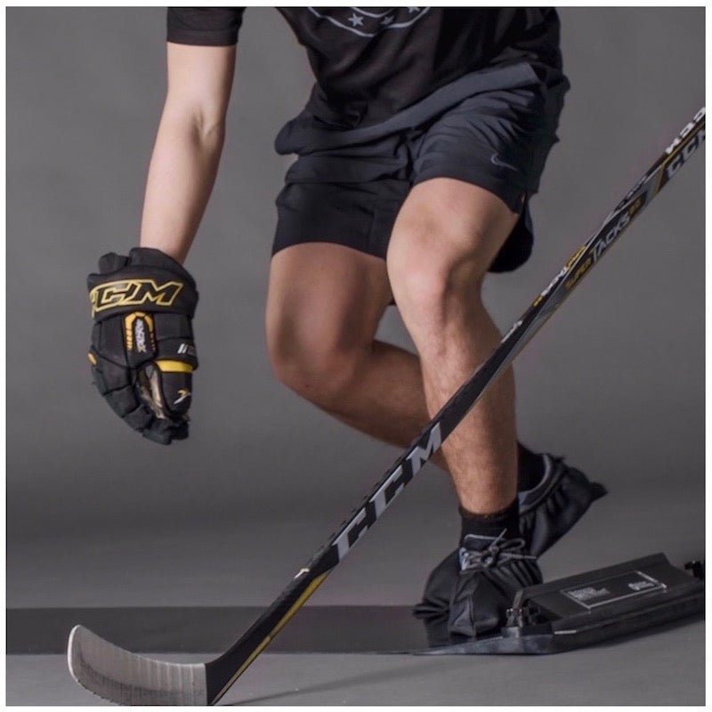 En spelare som använder en hockey slide board för att träna lateral rörelse och balans, klädd i hockeyutrustning.